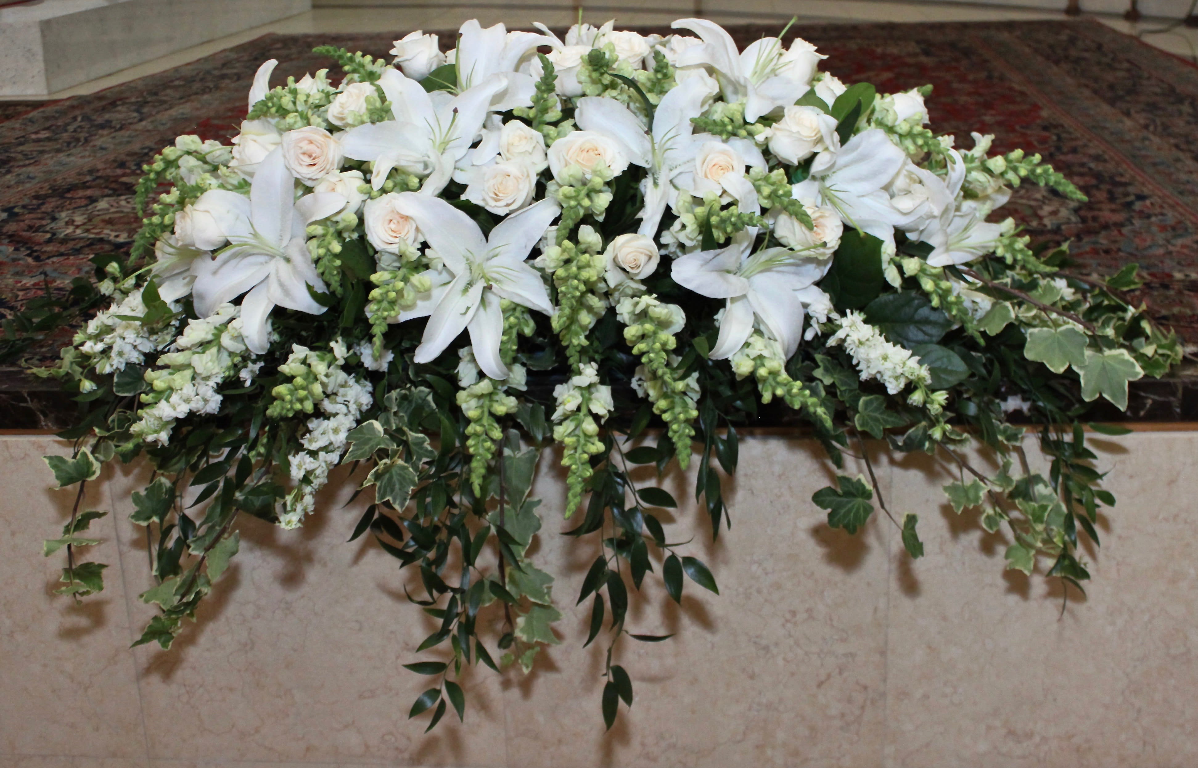 Ivy Stargazer Casket  - Full casket includes stargazer lilies and roses. We also include seasonal greens to this casket arrangement. 