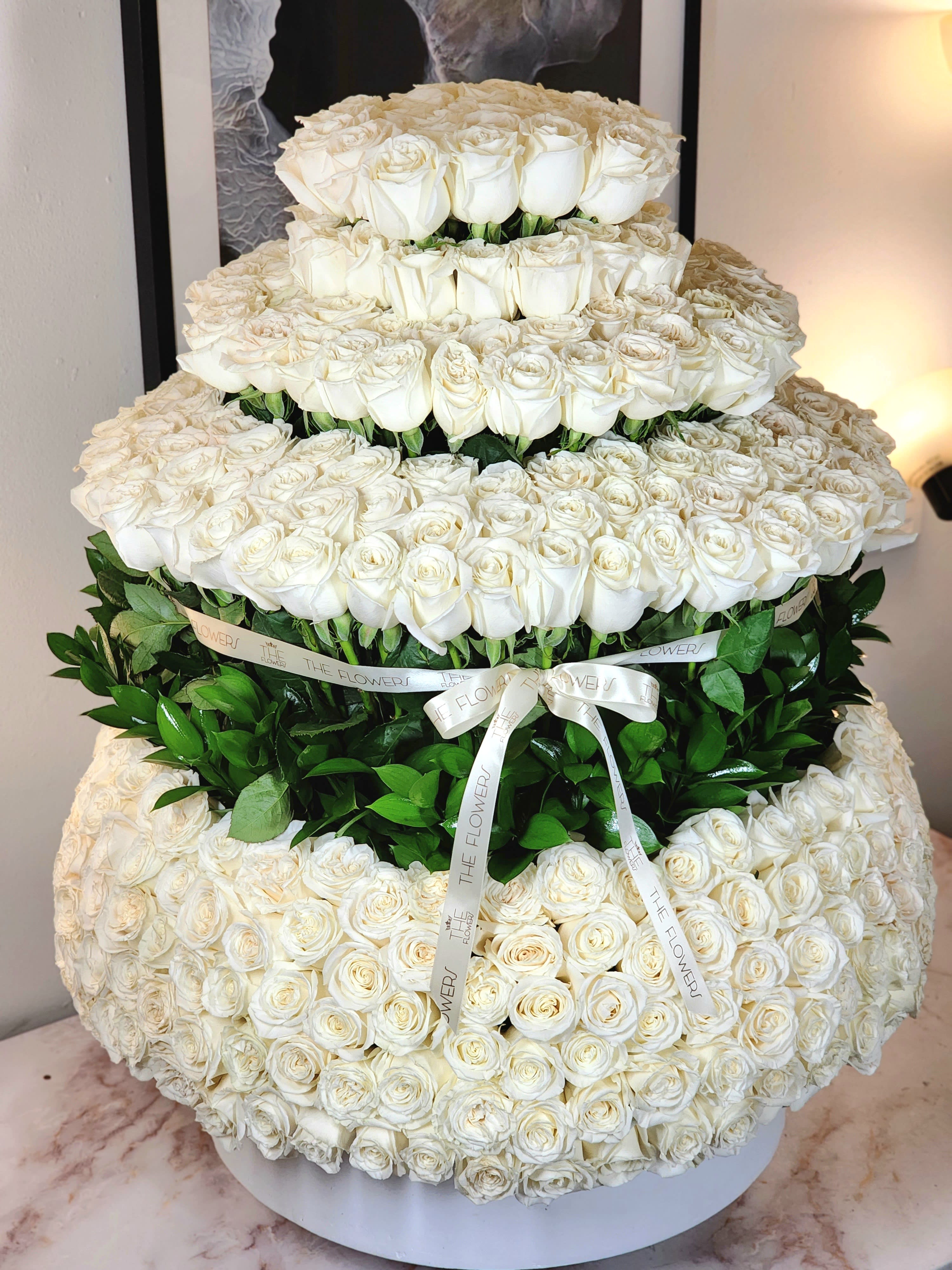 Wedding Cake  - A breathtaking display of 500 roses arranged in a towering masterpiece, reminiscent of a majestic floral tower. These celebrity blooms weave together seamlessly, forming a structure that captivates with its beauty. The design, resembling a colossal wedding cake, adds a touch of whimsy to the elegance, making it a truly stunning and unique floral arrangement.