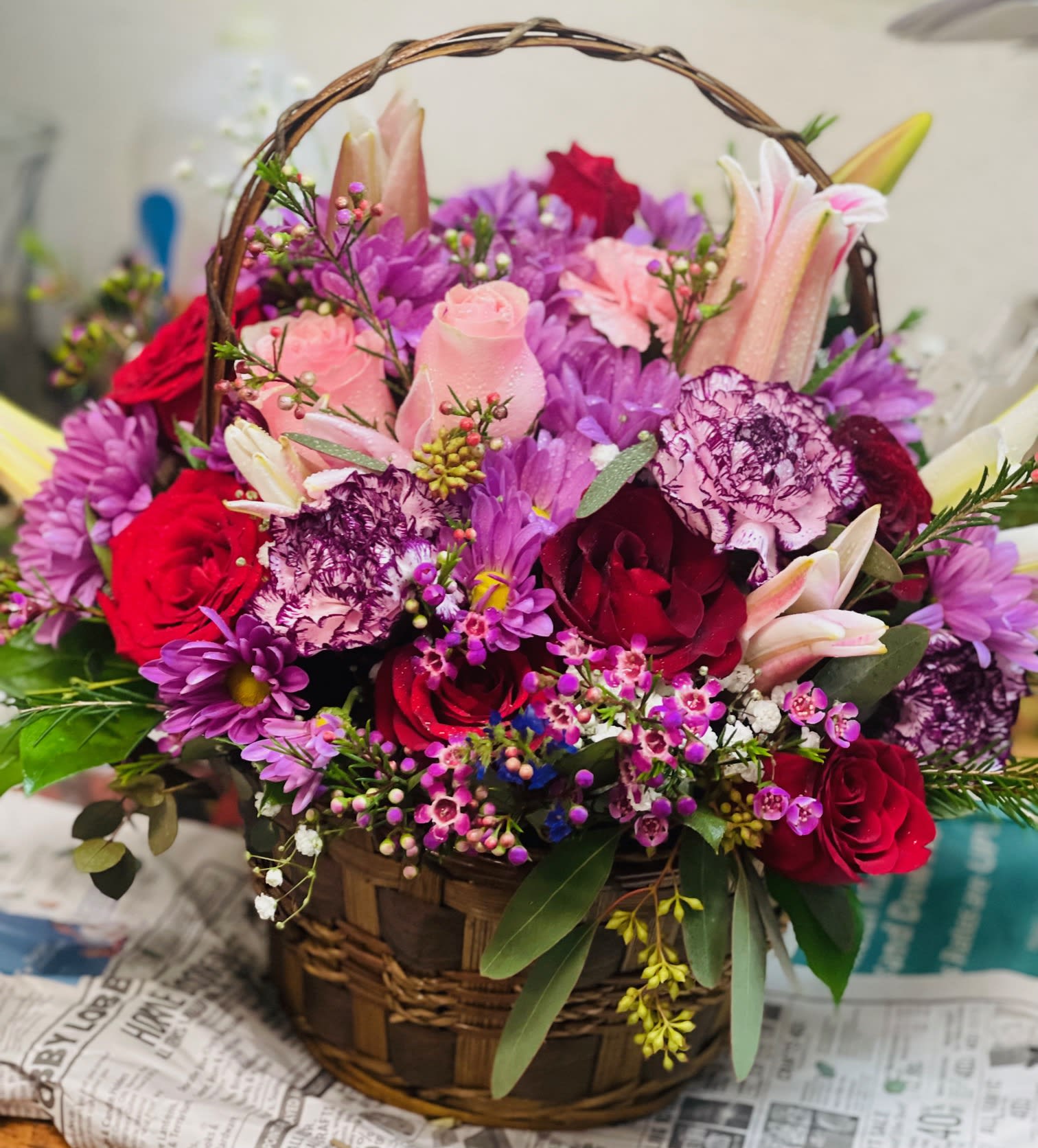 Royal Meadow Basket - Warm tones of reds, pinks and purples are featured in this bright and cheerful basket. A fresh assorted mix of roses, carnations, wax flower, statice, miniature carnations and lilies arranged in a bountiful basket will absolutely impress anyone. 