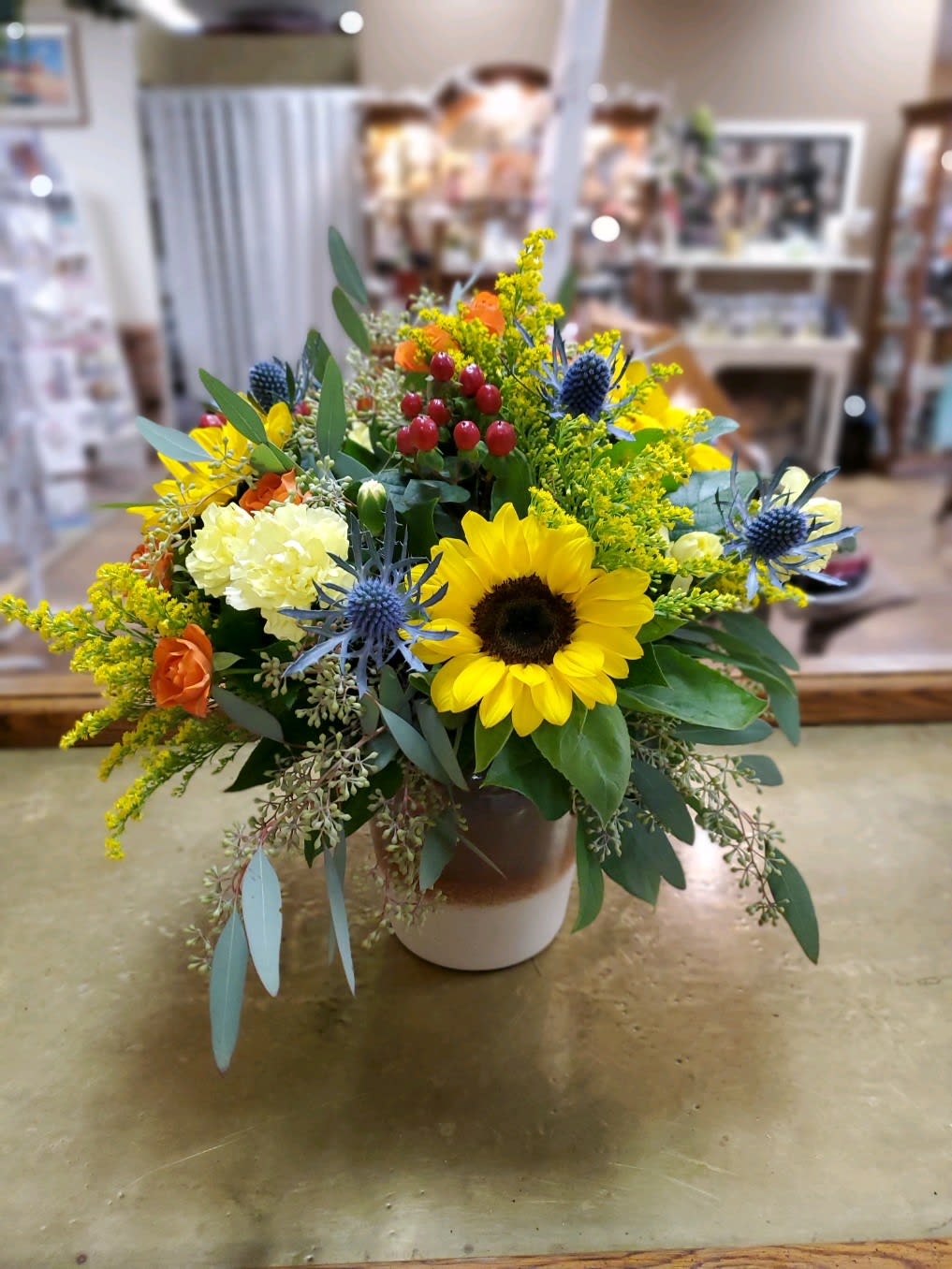 Rustic Sunrise Bouquet  - Sunflowers, thistle, spray roses, mini carnation, berries, filler and eucalyptus in a decorative container 