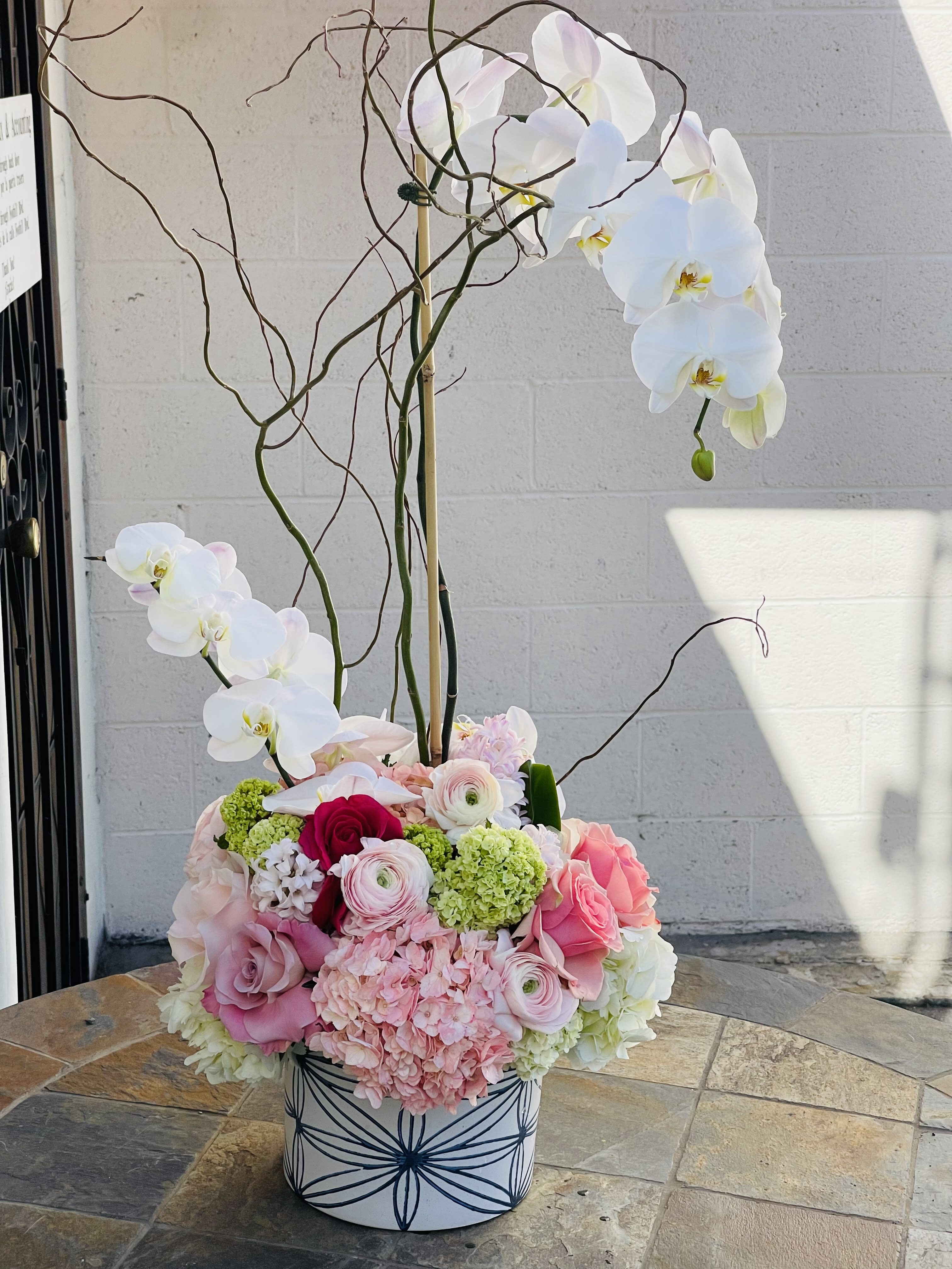 Single large orchid plant with flowers.  - This beautiful arrangement comes with a large orchid plant with flowers at the bottom. Surrounded by beautiful garden flowers.