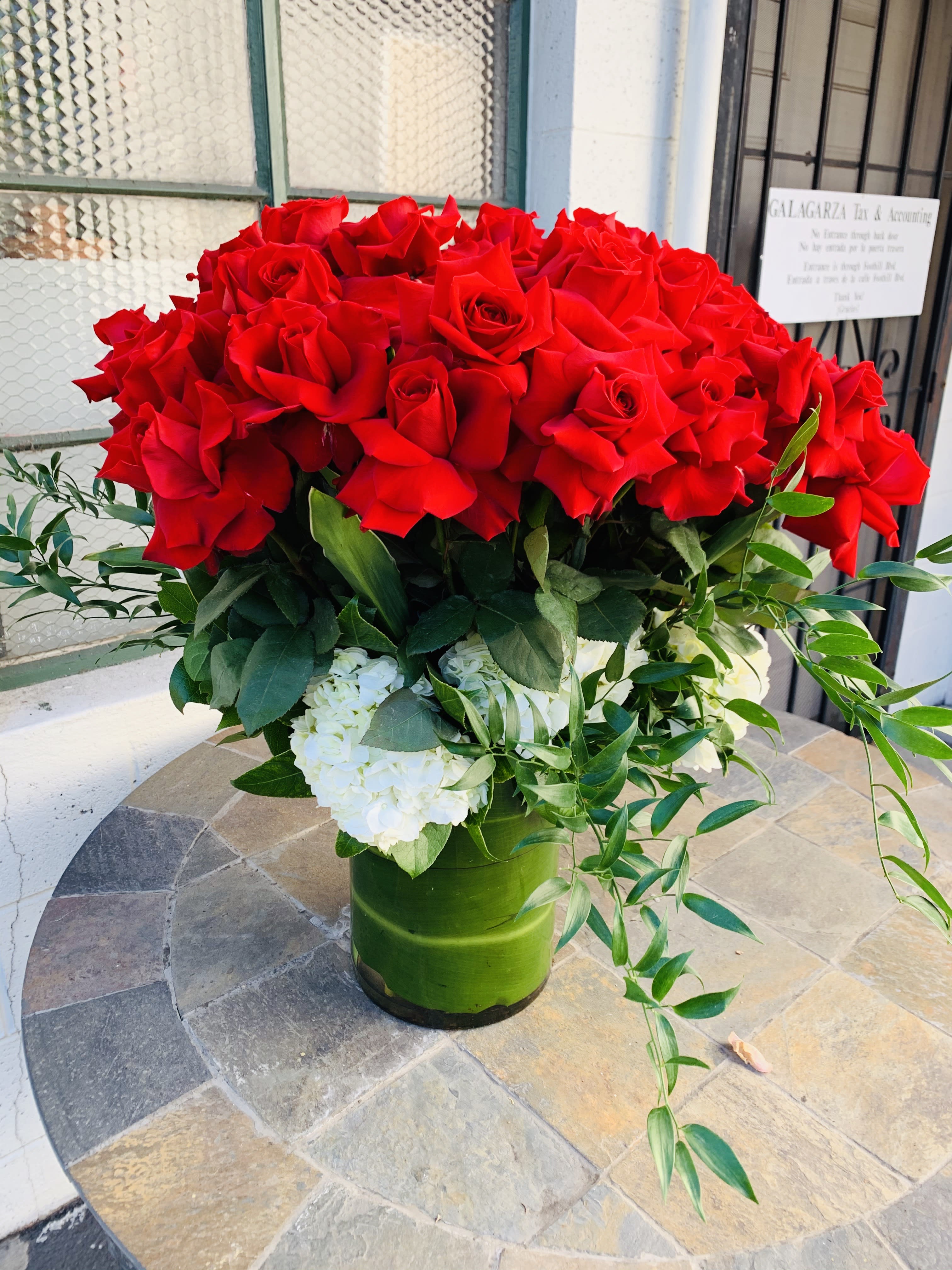 Red roses in vase covered in T leaves - Beautiful large rolls is all one height in large vase, with tea leaves covering the stands. Gorgeous stunning arrangement.