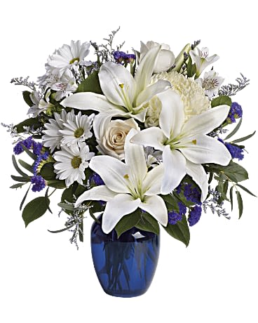 Beautiful in Blue - In this arrangement, the serenity of the color blue along with the purity of intention symbolized by white will let the family know you are sending your calm strength to them during these difficult times. Beautiful blooms such as blue hydrangea, crème roses, white lilies and alstroemeria along with yellow and white chrysanthemums, eucalyptus, limonium and more are beautifully arranged in a dazzling cobalt blue vase.Approximately 16 1/2&quot; W x 18&quot; H
