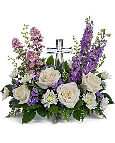 Poised with Love Bouquet - Soft and serene, this artistic array of cream and lavender blooms around a radiant crystal cross keepsake is a heartfelt expression of love. This beautiful piece includes crème roses, lavender larkspur, lavender montecasino asters, white cushion spray chrysanthemums, lavender sinuata statice, lemon leaf and dusty miller. Delivered with Teleflora's Small Crystal Cross.