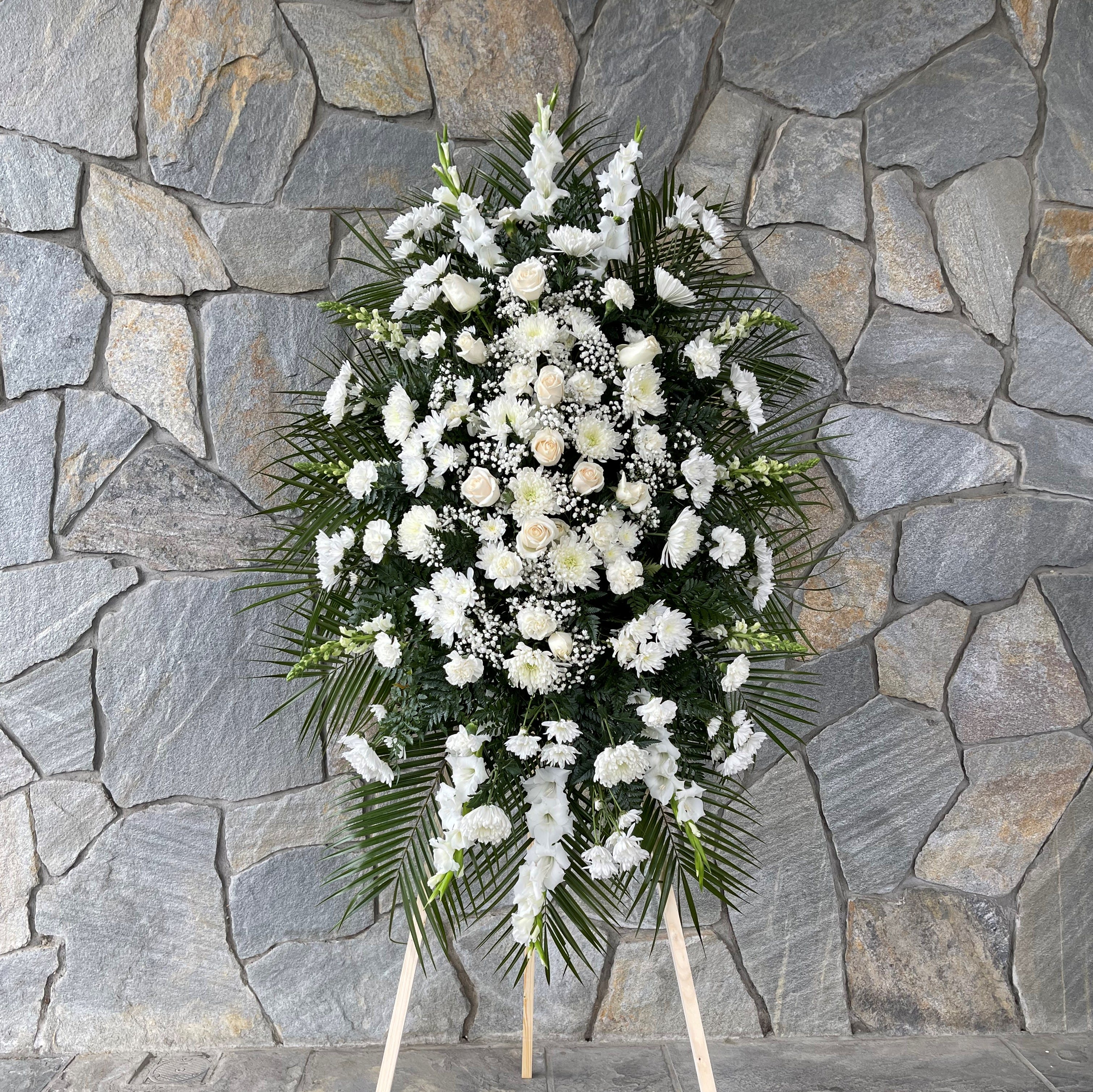 White Sympathy Standing Spray - White flowers create an aura of peacefulness and purity, bringing comfort and hope during a time of loss.  Our stunning standing spray arrangement is carefully crafted by expert florists with a bounty of pristine white blooms for a full, lush presentation.  Let it be a grand and memorable tribute to one who was loved so dearly.  All-white standing spray arrangement with roses, football mums, cremones, stock, snapdragons, carnations, daisy poms and monte casino; accented with soft, lush greenery. Premium measures approximately 58&quot;H x 40&quot;L without stand. Deluxe measures approximately 56&quot;H x 38&quot;L without stand. Standard measures approximately 46&quot;H x 34&quot;L without stand. Arrives on an easel. Appropriate for the funeral home or gravesite. Our florists hand-design each arrangement, so varieties may vary due to local availability.