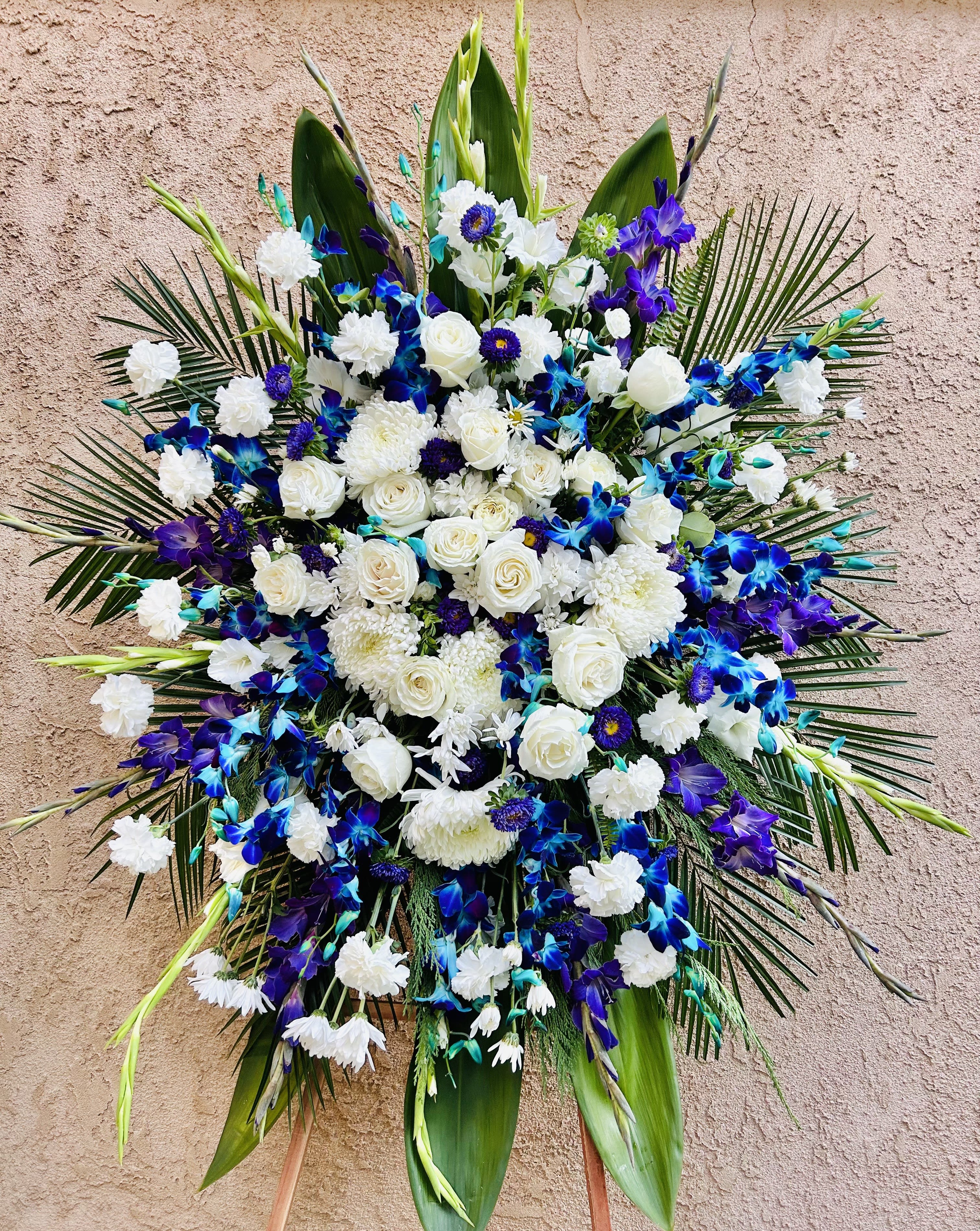 Rememberance - Beautiful blue and white floral spray featuring gladiolus, roses, chrysanthemum, daises, and green accents.
