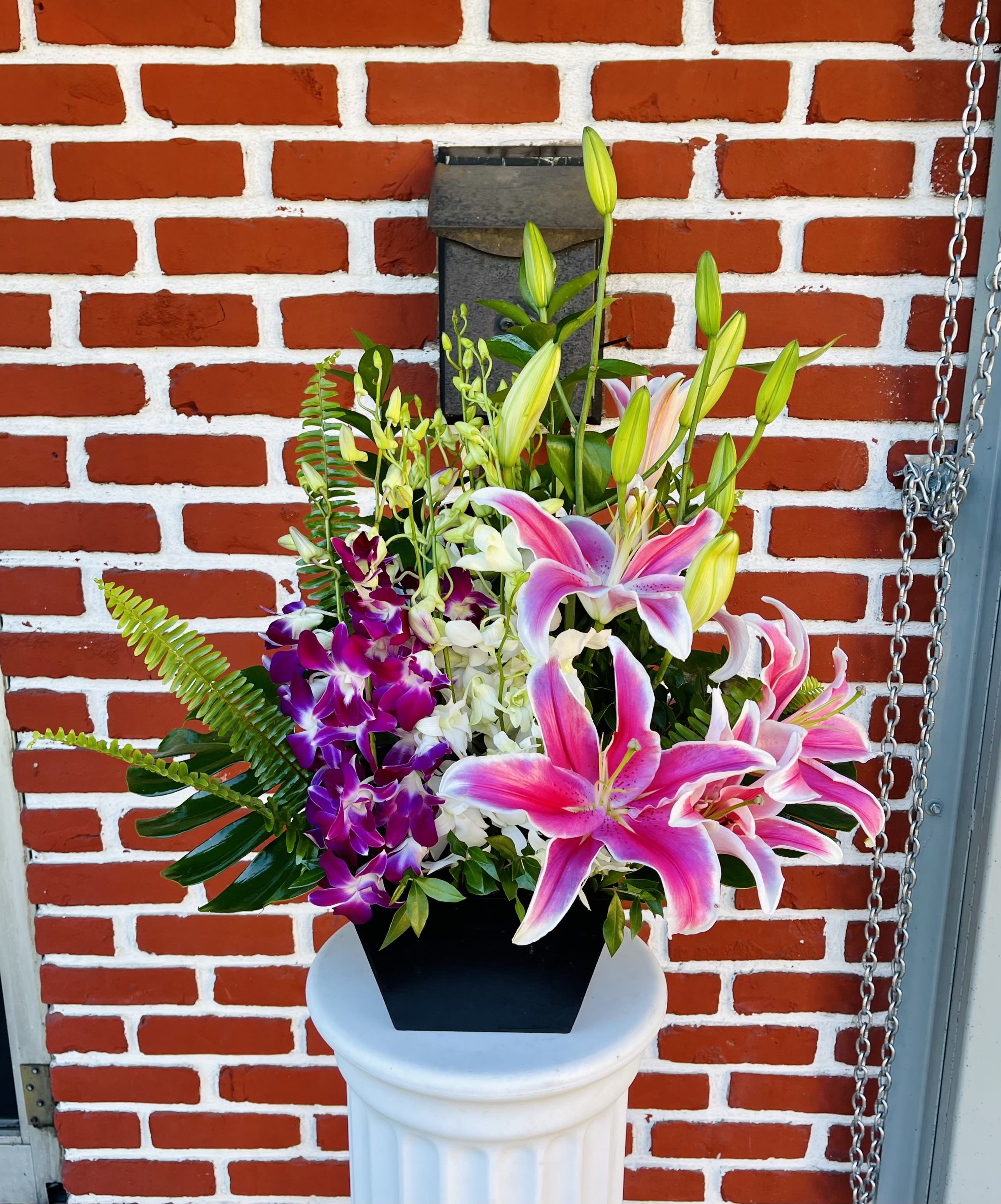 Tropical Orchid Lily Basket - A bright arrangement of purple and white orchids, pink stargazer lilies, and tropical greens.  Our florists hand-design each arrangement to be as fresh as possible, so colors and varieties may vary due to availability.