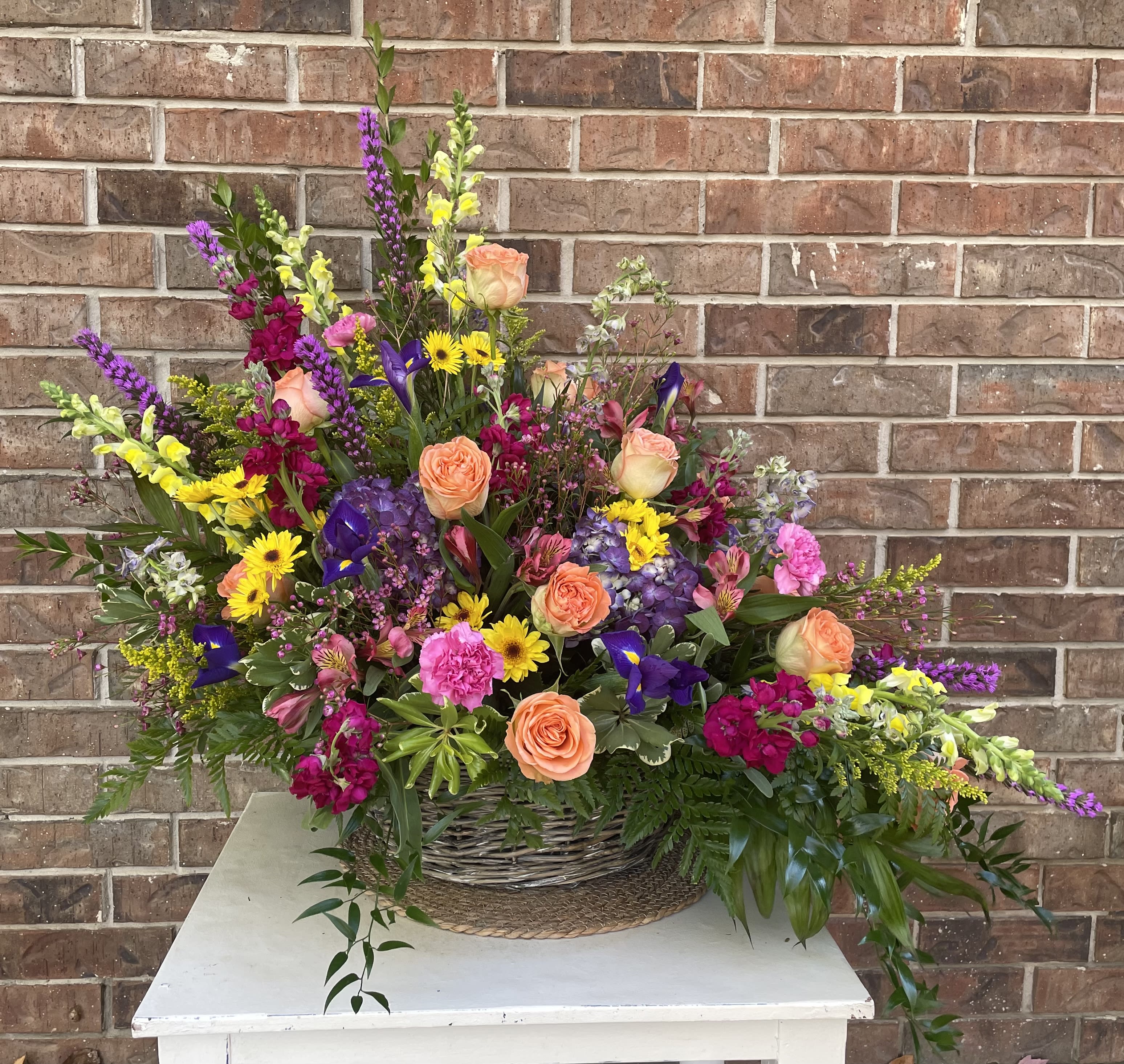 Garden Basket Garden Basket - A large beautiful grey willow basket filled with a lush variety of flowers. Stunning wild flower look and feel while still keeping it traditional. Standing with a stunning stature this is sure to be the spotlight for any occasion. Colors can be changed due to availability.