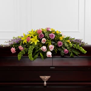 The FTD Forever Beloved Casket Spray - The FTD® Forever Beloved™ Casket Spray beautifully illuminates the atmosphere of their final farewell service. Lavender roses pink roses lavender larkspur pink carnations Bells of Ireland yellow Asiatic lilies yellow freesia solidago and lush greens are arranged to create an extravagant display of floral beauty that offers comfort and peace to the friends and family of the deceased.