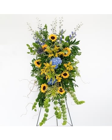 Summer Fields Standing Easel Spray - This incredible spray from the Summer Fields Collection is beautiful with bells of Ireland, bells of Ireland, shocking blue hydrangeas, sunflowers, solidago and thistle with curly willow, lemon leaf and song of India foliage.