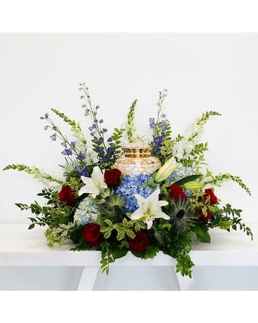 Courage Cremation Piece - These amazing cremation flowers from the Courage Collection are stunning with blue delphinium, blue and white hydrangea, while lilies, mums, red roses, snapdragons, with thistle, huck and lemon leaf foliage.