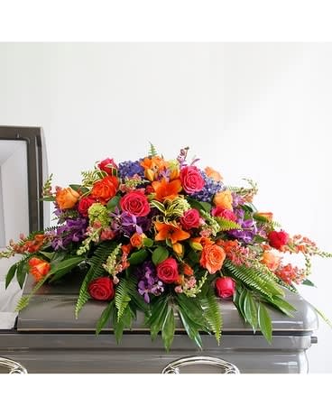 Bright Remembrance Casket Spray  - This incredible casket spray from the Bright Remembrance Collection is stunning with hot pink and free spirit roses, orange and pink snapdragons, purple mokara orchids, purple and mini green hydrangea, fragrant orange lilies, with ferns and lemon leaf foliage.