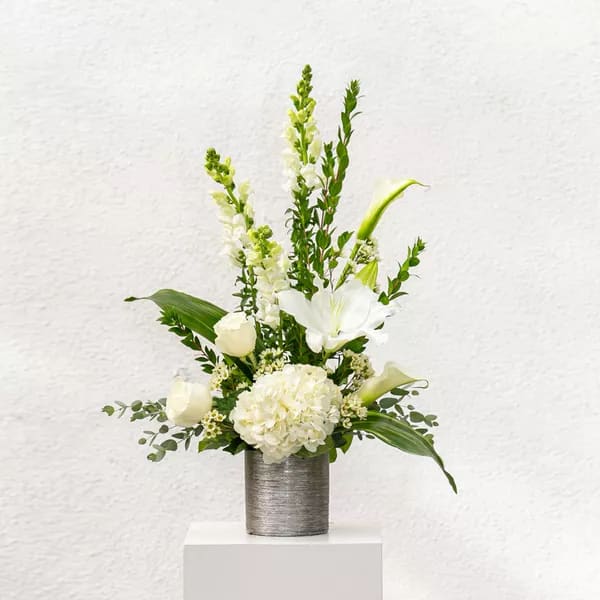 Eternal Day - Pay your respects to a loved one with this all-white rose, hydrangea, stargazer lily, calla lily, and snapdragon piece. 