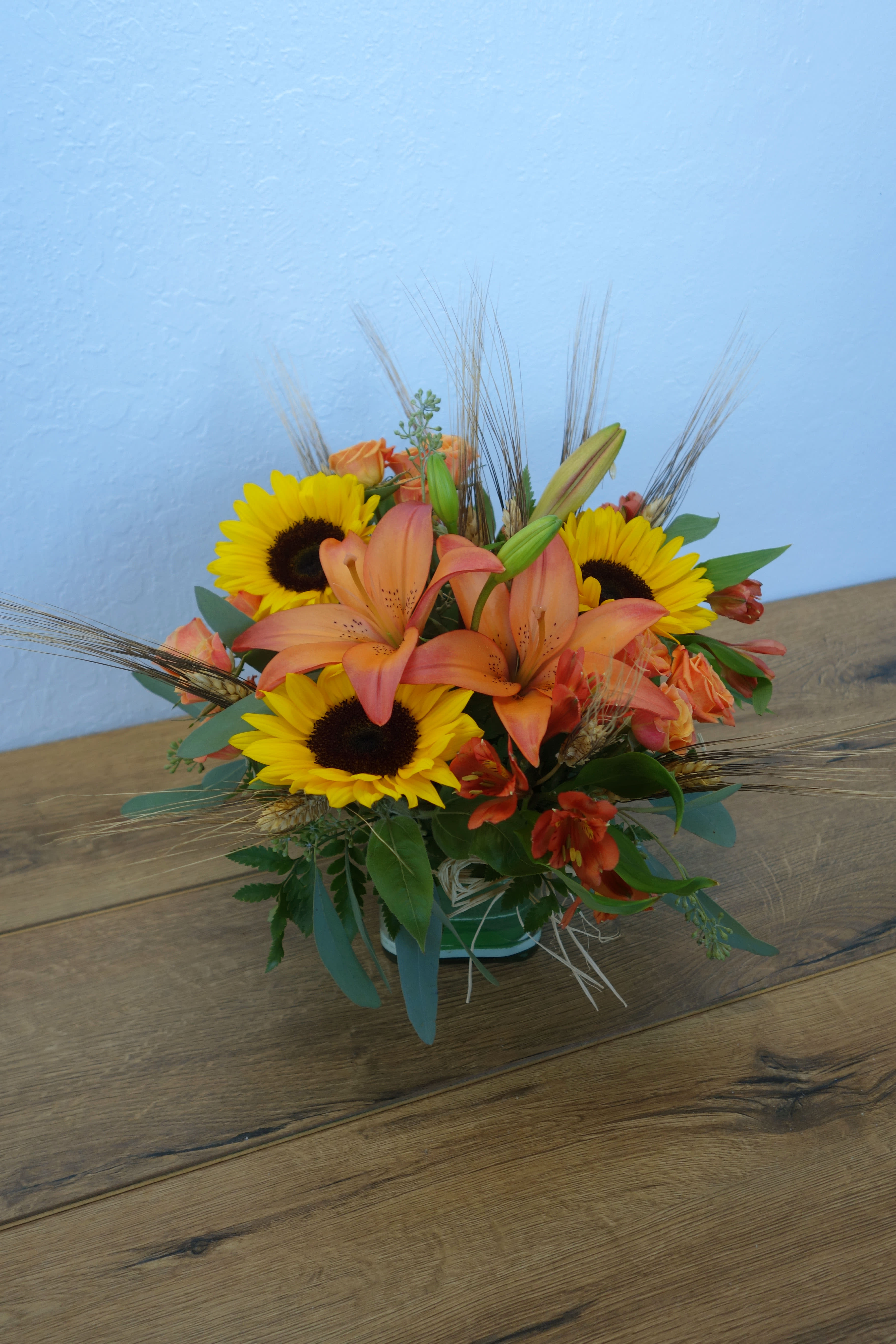 Autumn Expression Bouquet - Bring a bright contemporary touch to this glorious season with a fall bouquet in a clear cube vase. It's a great gift for faraway friends. The stylish contemporary arrangement includes sunflowers, lilies, carnations, roses, wheat and greens.  Orientation: All-Around