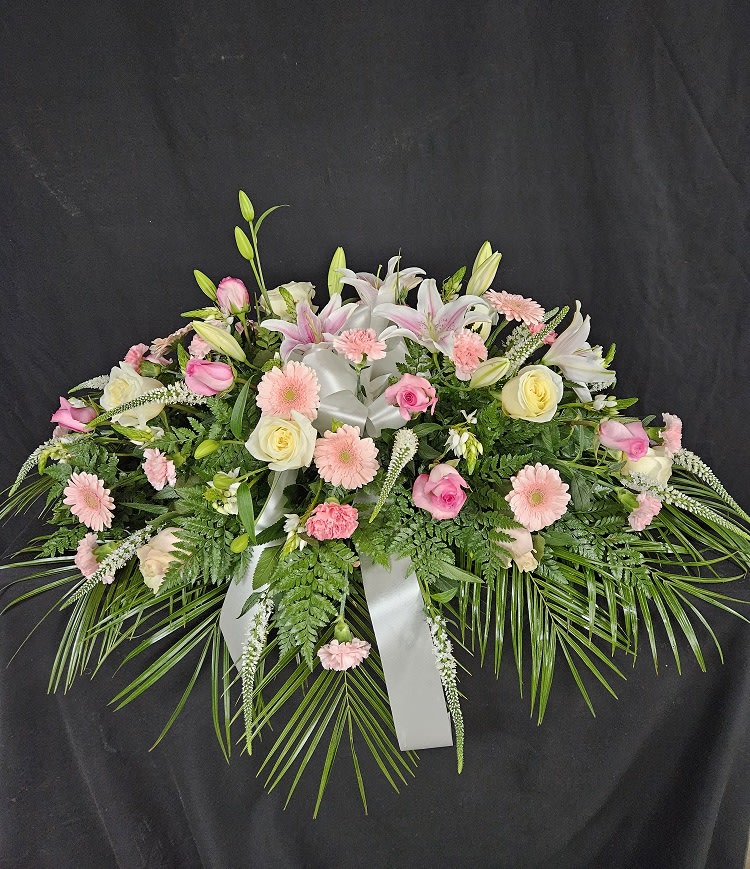 Shades of Pink Casket Spray - Shades of pink and purple laid over a bed of greens. Includes pink roses, pink carnations, purple/pink/white stock, pink mini carnations, and purple liatris. Price includes up to 4 custom printed ribbons.