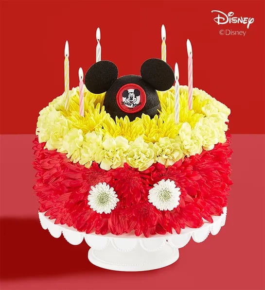 191049 Disney Mickey Mouse Flower Cake - A whimsical take on birthday cake? We’re all ears! Part of our new Disney collection, our signature flower creation is hand-crafted in red and yellow blooms to resemble Mickey Mouse’s iconic pants—complete with buttons. It’s topped with a genuine replication of the original Mouseketeer hat, adding charm and nostalgia to their celebration.