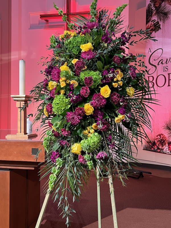 Purple  Green and Yellow Standing Spray - Standing five to six feet tall on a stand, an arrangement of seasonal blooms in purples, greens and yellows. Individual varieties will vary according to the season.
