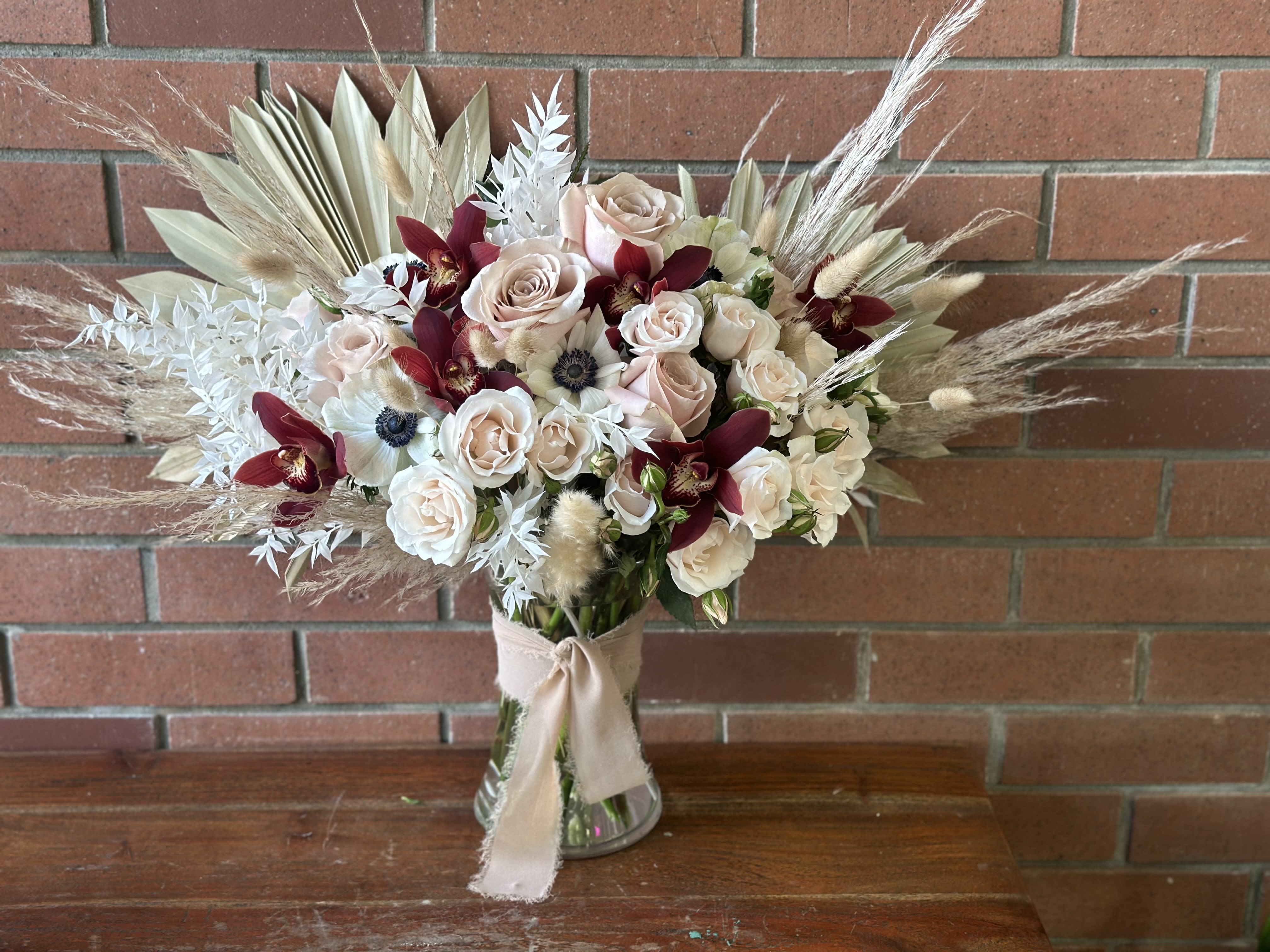 Heavenly  - Send this Heavenly bouquet full of lush red orchids, pale mauve roses, anemones, blush spray roses, preserved palms, bunny tails, pampas grass and Italian ruscus - once the fresh flowers live out - the gift of the preserved left over flowers will last for many years to come.  Arranged in a clear vase wrapped with soft chiffon ribbons.  Each size up will include a larger vase with the added value of fresh and preserved flowers to make it even bigger and showier. 