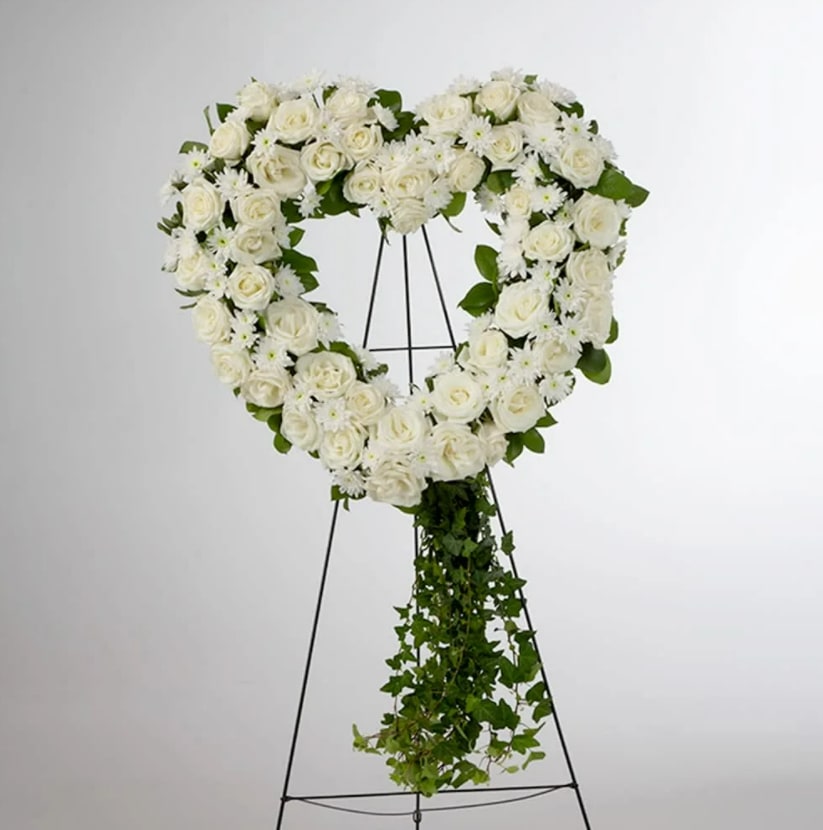 Love in our Hearts by BloomNation™ Love in our Hearts by BloomNation™ - An all white tribute, this heart shaped easel shows your everlasting love. Featuring a variety of white flowers and greenery, this heart with a trail of ivy compliments the beauty of life.