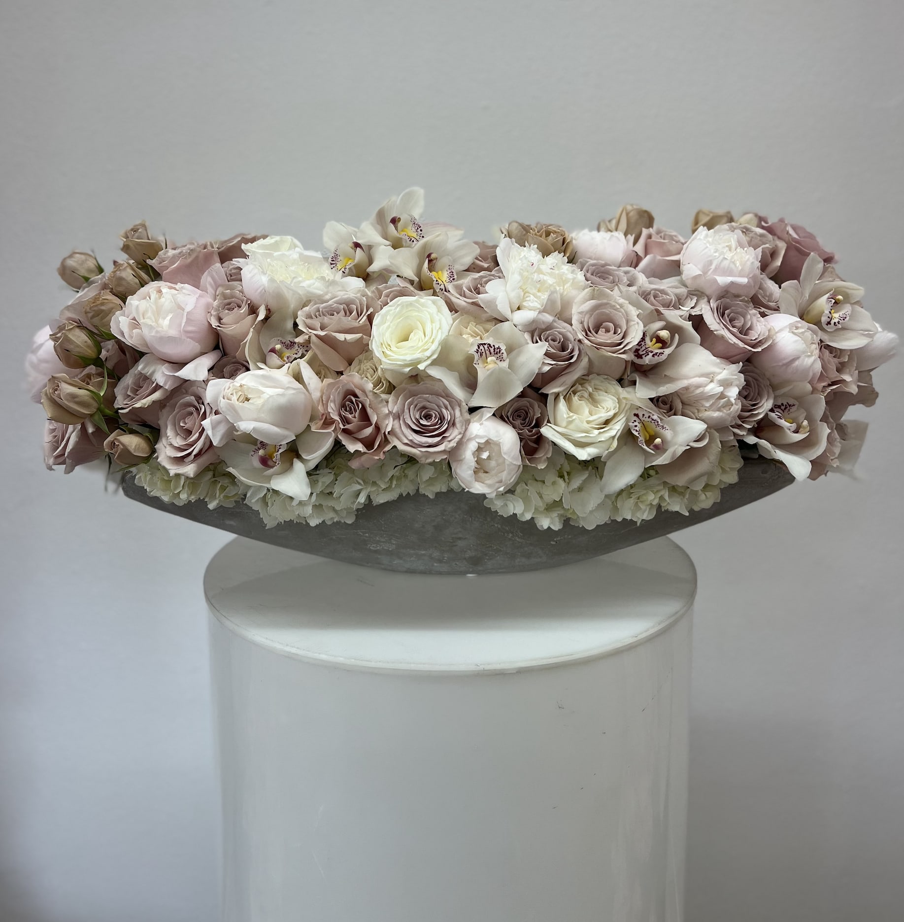 Coco love - Bring beauty to the table with elegant arrangement, presented in a long cement vase. This arrangement features roses, orchids, peonies, spray roses, and hydrangea.   Due to the seasonality of flowers or supply chain issues, substitutions may occasionally need to be made. While we understand this is an inconvenience, we will fill your order with an arrangement of similar color and design style.