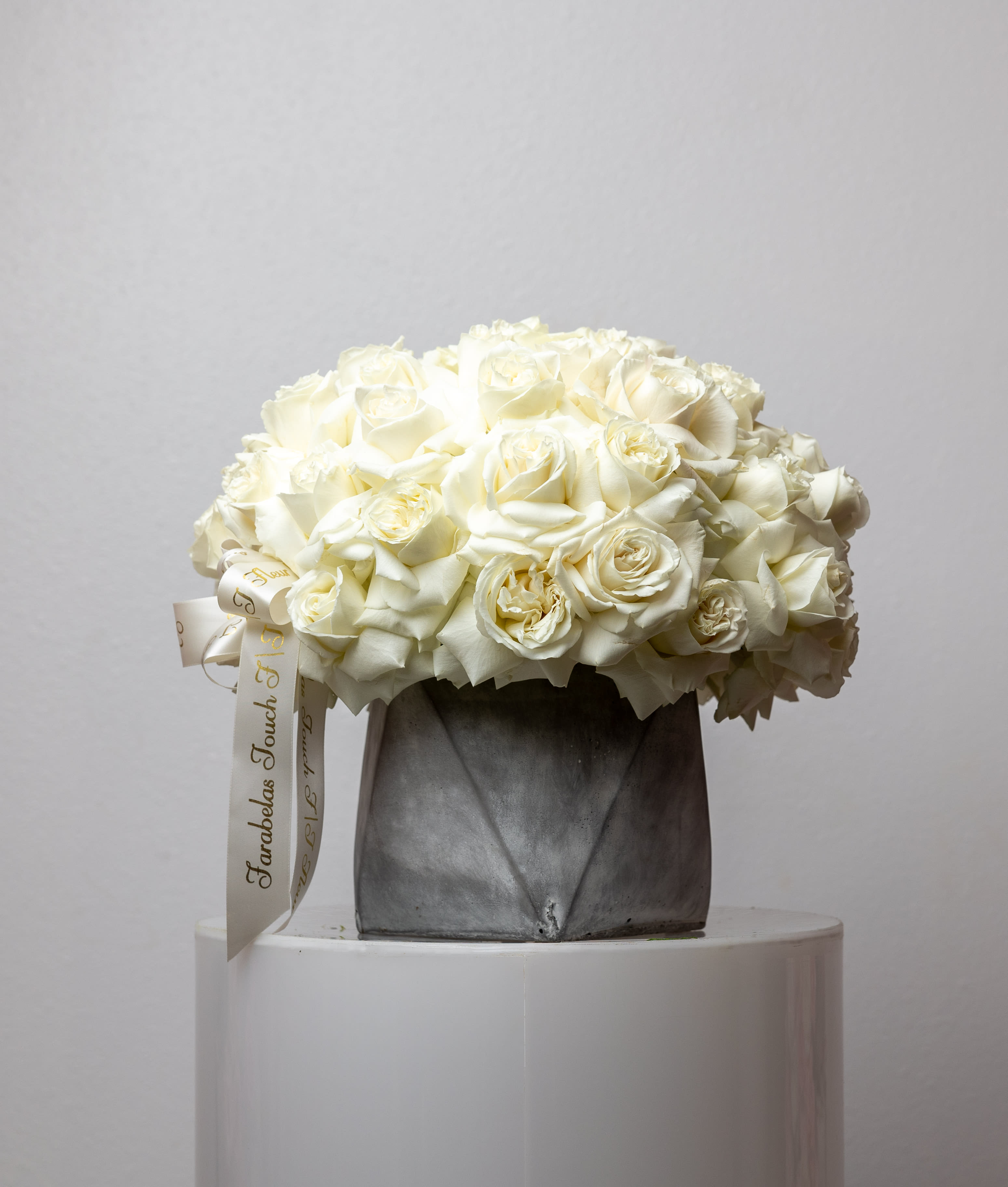 Moon - Bring beauty to the table with elegant arrangement, presented in a cement vase. This arrangement features roses all around.   Due to the seasonality of flowers or supply chain issues, substitutions may occasionally need to be made. While we understand this is an inconvenience, we will fill your order with an arrangement of similar color and design style.