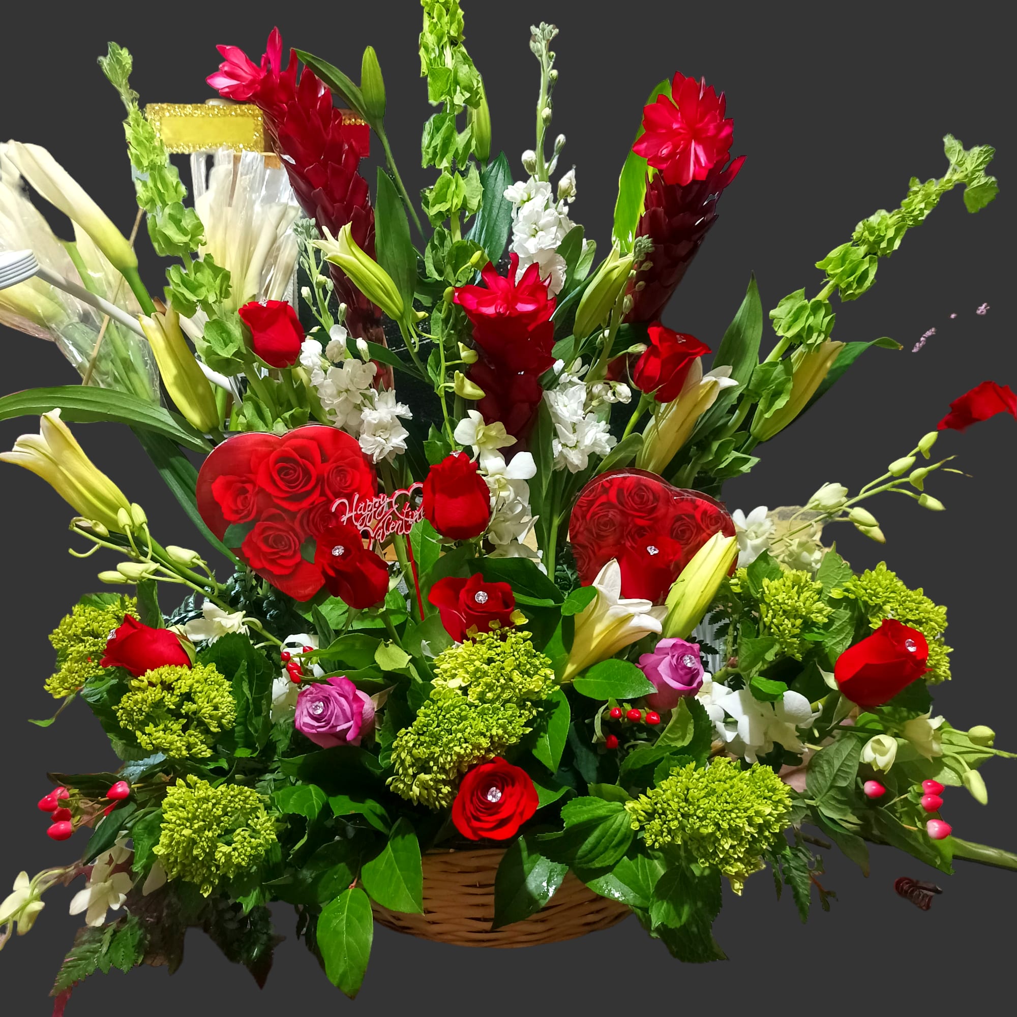 Large Tropical Floral basket with Heart Shaped Chocolates Large Tropical Floral basket with Heart Shaped Chocolates - The best of the best, this is a huge extremely large centerpiece filled with exotic flowers and two boxes of heart shaped chocolates. A mix of tropical red ginger flowers, bells of ireland flowers, red roses with diamond pins, yellow solidago fillers, hypericum red berries, lavender roses with diamond pins, white dendrobium orchids, white stock flowers and exotic greenery, expertly designed in a large basket.