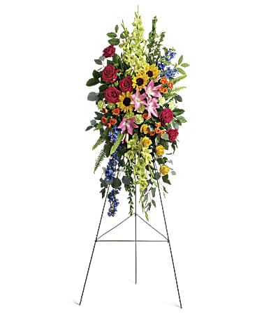  Love Lives On Spray - Bursting with joy, this radiant spray of rainbow blooms is an exuberant tribute to never-ending love.  This spray features hot pink roses, yellow roses, orange spray roses, pink asiatic lilies, green gladioli, green carnations, medium yellow sunflowers, blue delphinium, bupleurum, myrtle, sword fern, silver dollar eucalyptus, and lemon leaf. Delivered on a wire easel. 