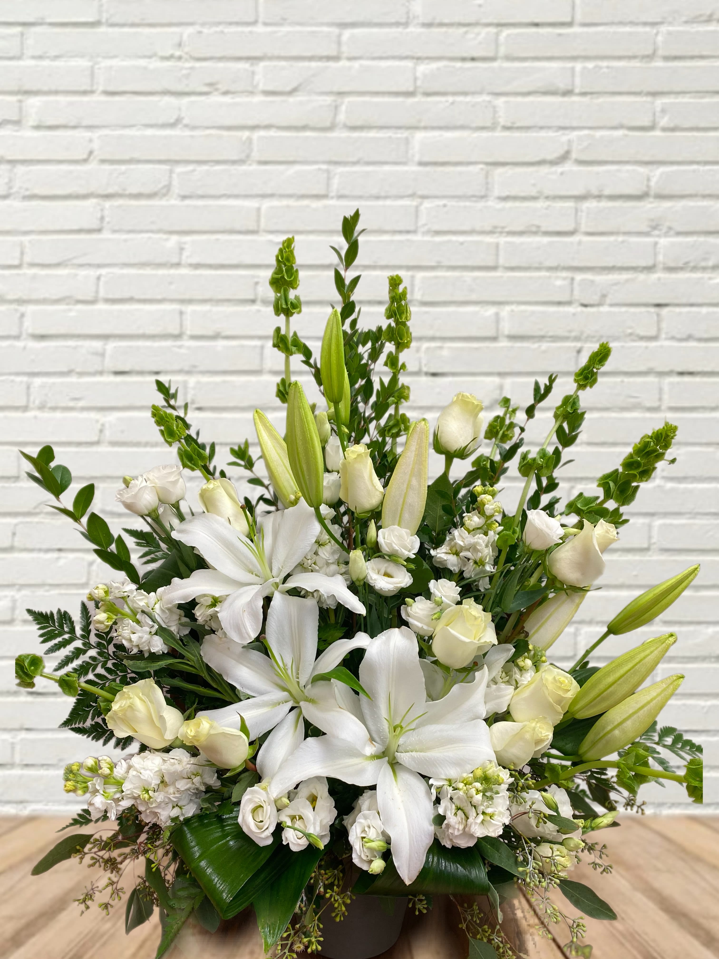 Woodland Dream Woodland Dream - All white floral display with lilies, lisianthus, roses, bells of ireland, stock, and assorted greens in a nice pot.