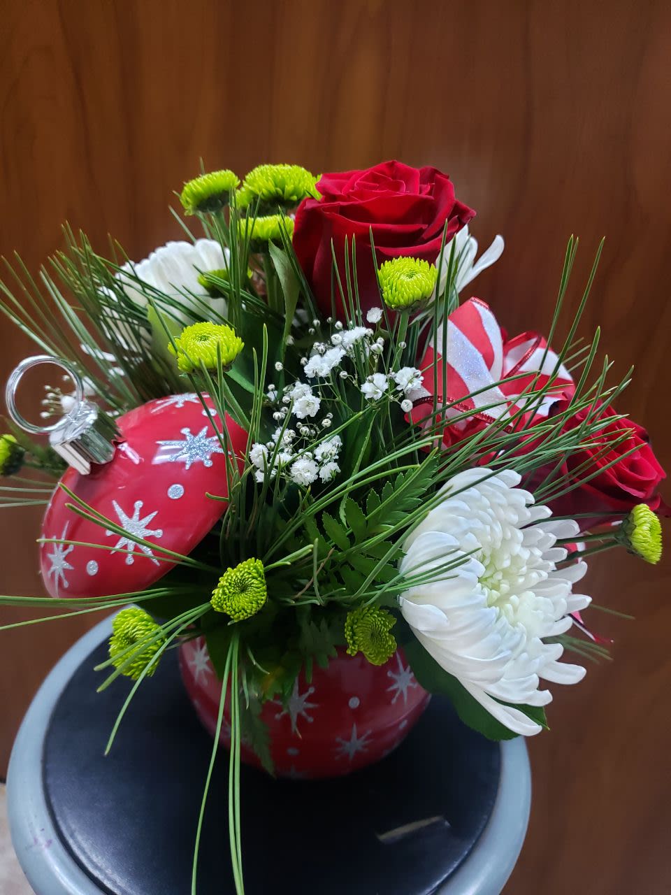 The Magic Of Christmas - 3 red roses,3 white spiders mum, 3 green buttons, white baby breath, 2 pinecones,  in a very pretty red sphere shape vase  that comes with its lid.