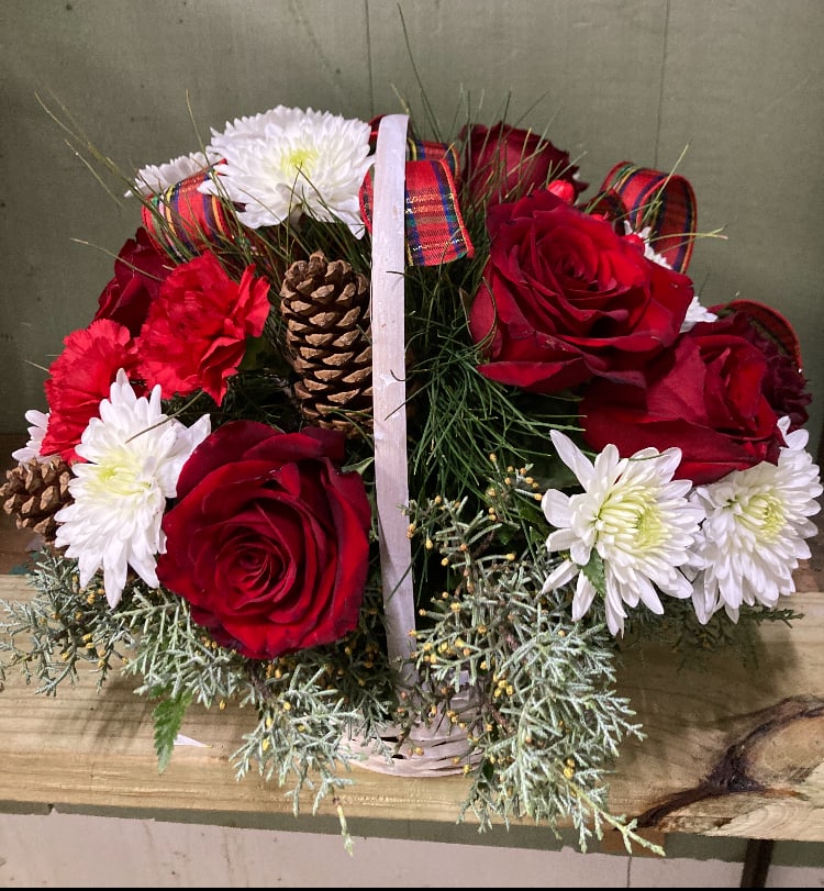 A Christmas Basket - Red roses and red carnations with white mums and pine cones in a basket with a handle.