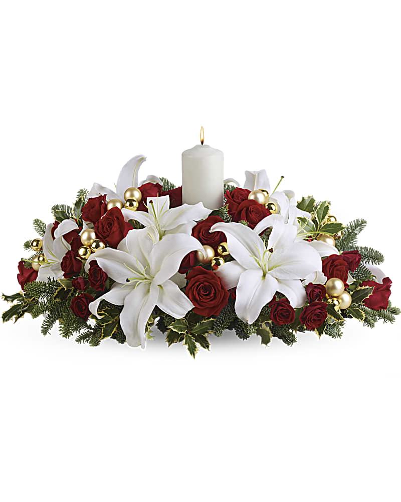 Luminous Lilies Centerpiece Luminous Lilies Centerpiece - Classic Christmas colors and holiday cheer are echoed in this beautiful centerpiece of red roses, white asiatic lilies, noble fir and holly branches. One white candle gives the centerpiece a subtle glow