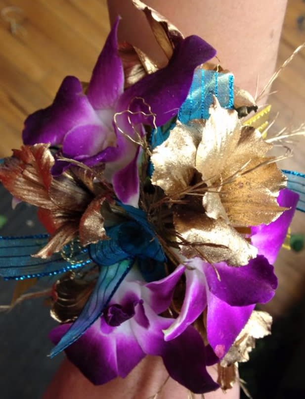 Purple Orchid Wrist Corsage Purple Orchid Wrist Corsage - Purple Orchids and gold alstromaria make this corsage one of a kind! It's accented with turquoise ribbon and gold fern. A show stopper!