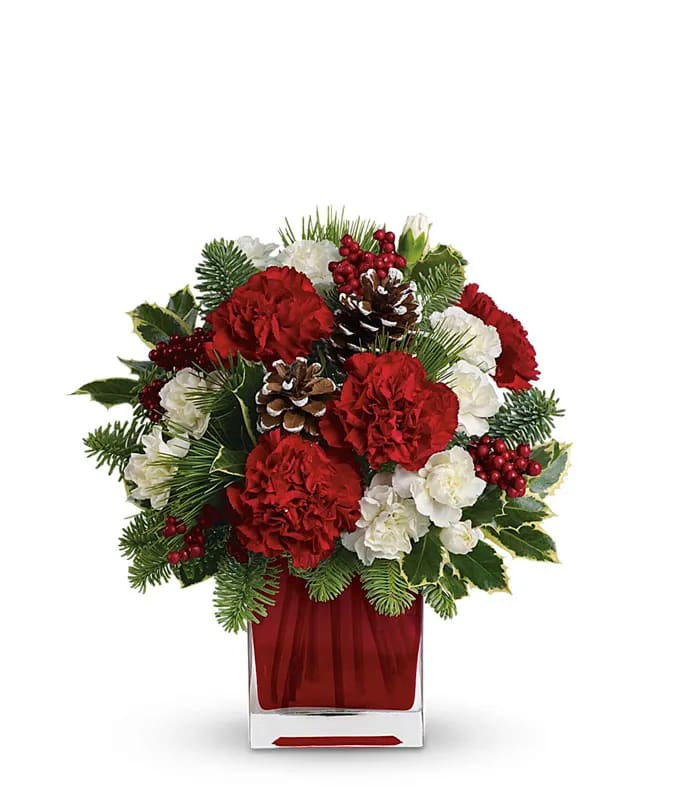 The Christmas Spirit Bouquet - Send a sweet holiday message with this seasonal bouquet. Red and white carnations, holiday greens and decorative pinecones designed in a bright red cube vase.