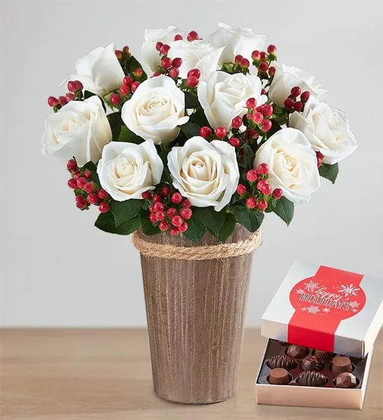 Holiday Happiness Bouquet  - This charming holiday bouquet paris snowy white roses with red berries to wish the people you love a season full of joy.  This arrangement comes with a total of 12 white roses and 10 stems of red hypericum berries in a rustic wooden vase with delicious chocolate 