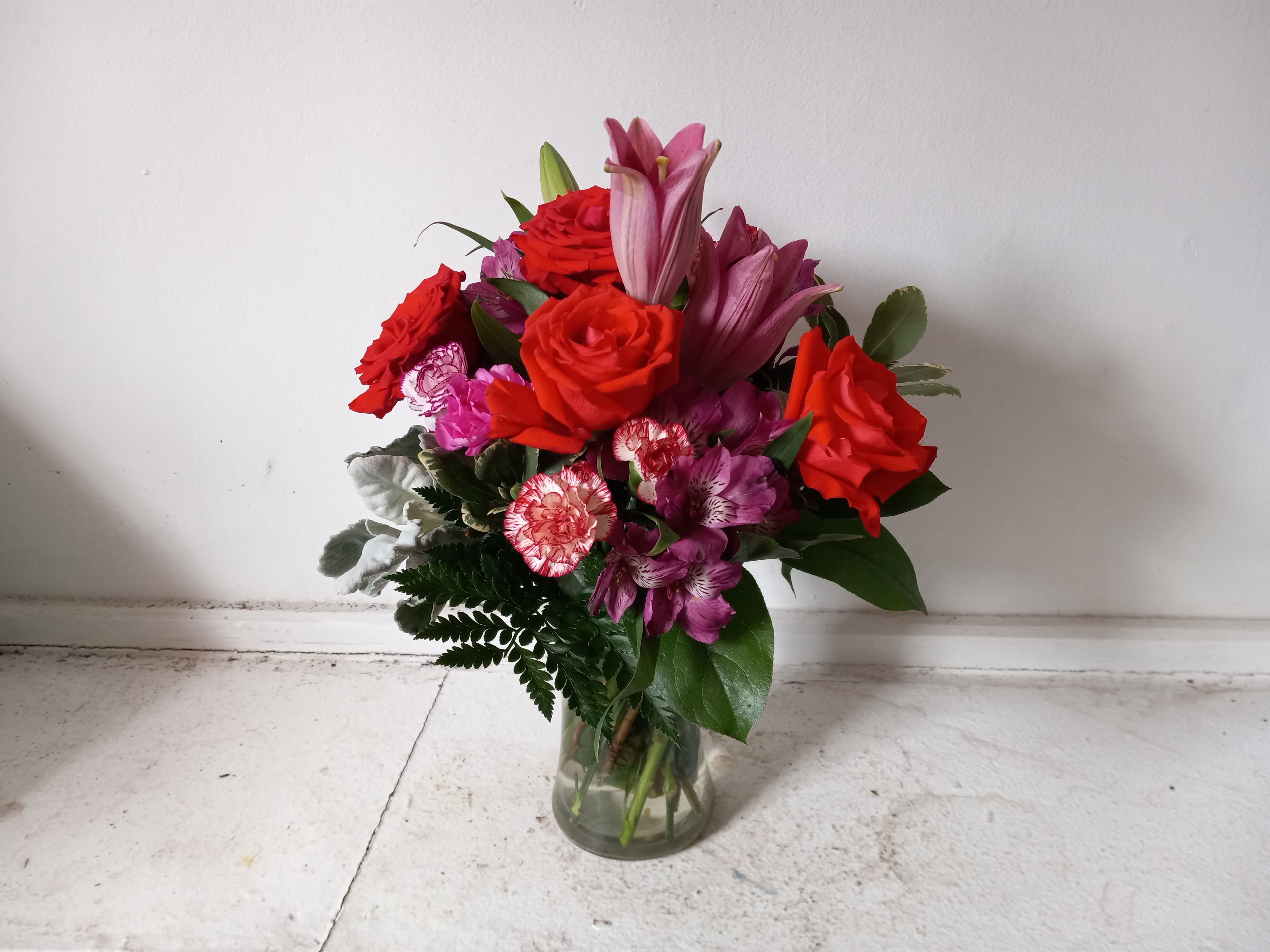 &quot;Teresa&quot; - Beautiful orange roses mixed in with pink lilies, purple/pink alstroemeria and light pink spray carnations in a glas vase 