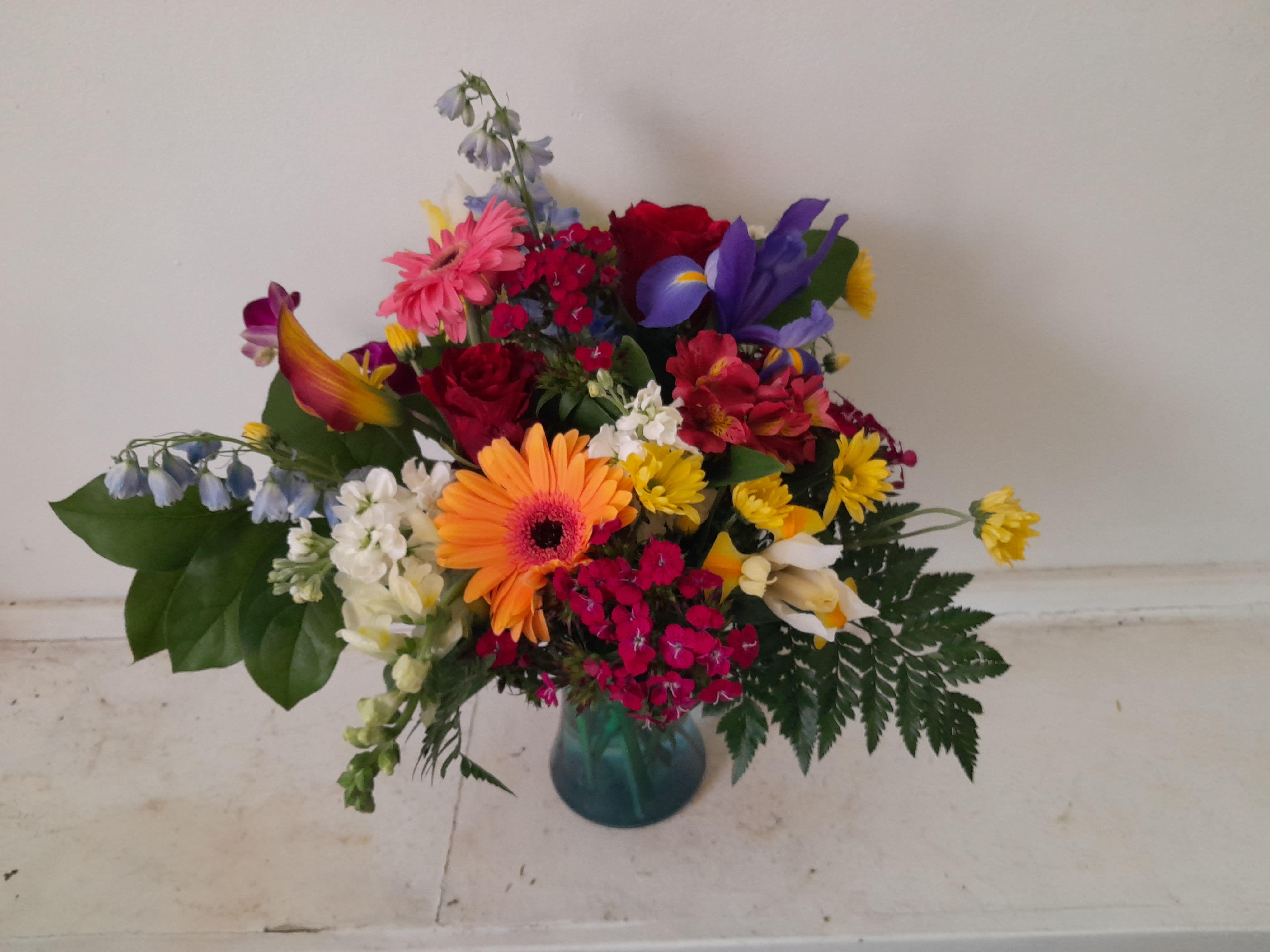 Summer rain - Beautiful bright mix of colors, orange gerbera daisy, hot pink sweet William and snap dragons, blue and yellow Irises, blue delphinium, yellow daisies in a vase