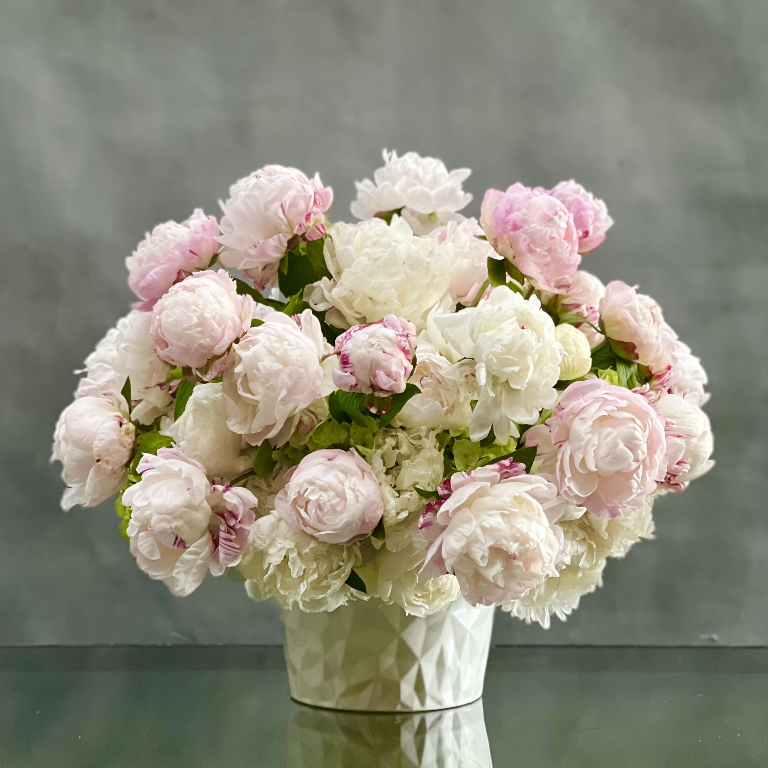 Pure Peony Perfection - Graceful and stunning over 70 blooms of blush and white peonies nested on white hydrangeas in a geometric pot