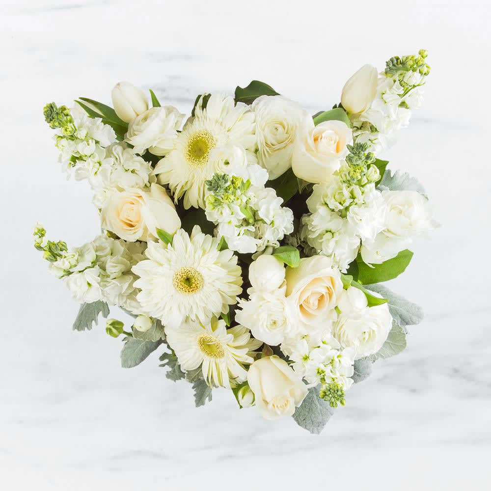 Purity by BloomNation™ - This arrangement contains gerbera daisies, roses, tulips, stock, and other seasonal blooms. APPROXIMATE DIMENSIONS: 15&quot; D x 13&quot; H