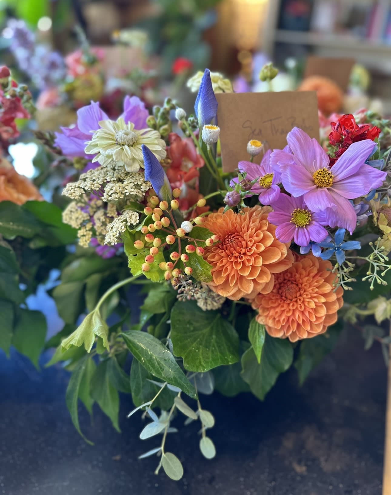 Jewel Toned Beauty Jewel Toned Beauty - This sweet arrangement is filled with a variety of florals in shades of blue, orange, purple and reds! Perfect for any occasion to bring cheer to your loved one's day!