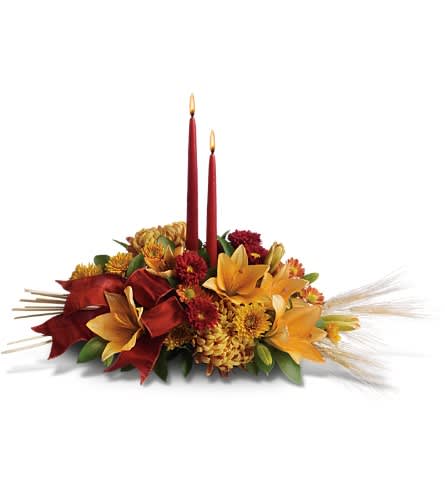 Graceful Glow Centerpiece - Make Thanksgiving all the more special by bringing a graceful glow to the table. Everyone will be filled with gratitude in the presence of such beauty. Delightful red roses orange asiatic lilies orange and bronze chrysanthemums and burgundy ribbon surround two elegant taper candles. Accents of natural wheat make this gift wildly festive!Approximately 26&quot; W x 17 1/2&quot; H Orientation: All-Around As Shown : T168-1ADeluxe : T168-1BPremium : T168-1C