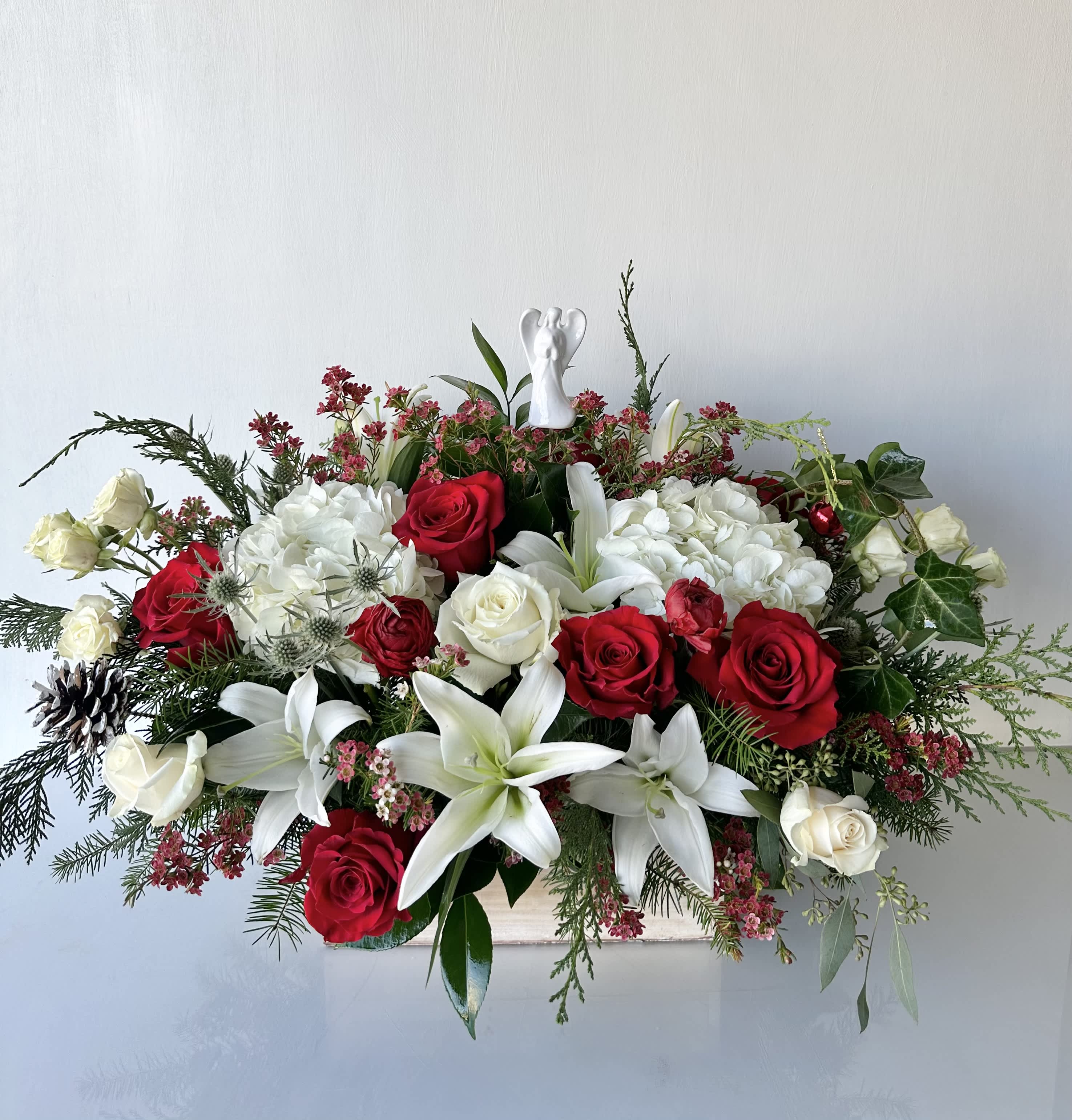 Christmas Love - A centerpiece of fresh-cut flowers in red, white, and greenery with an angel symbol.