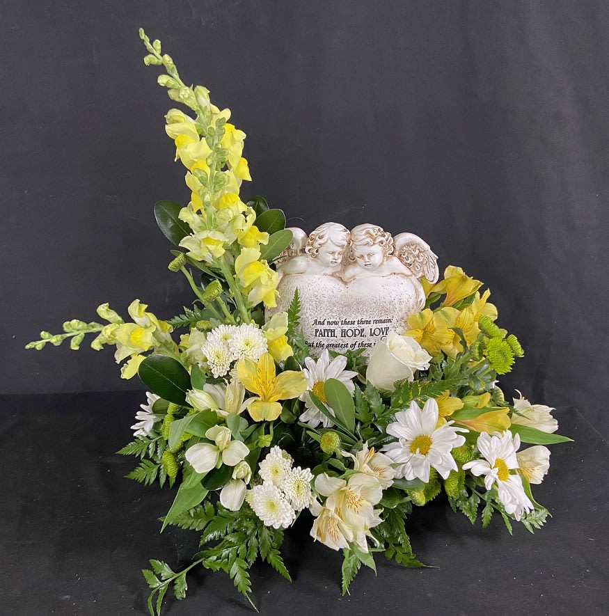 Faith, Hope, Love - &quot;And now these three remain, FAITH, HOPE, LOVE, But the greatest of these is LOVE&quot;. This beautiful memorial contains a heart and cherub keepsake stone surrounded by white roses, yellow snapdragons, white daisies, and yellow and white alstro. Color substitutions available upon request.