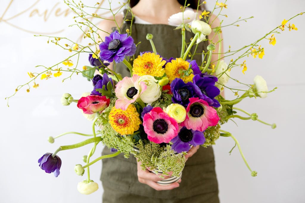 Ammome, Rananculus, orchid, queen anne's lace with greenery - Introducing our exquisite floral arrangement, a harmonious blend of sophistication and natural beauty. This stunning ensemble features a curated selection of premium blooms, including Ammome, Ranunculus, orchids, and the delicate elegance of Queen Anne's Lace. Each blossom has been thoughtfully chosen to create a bouquet that not only captivates the senses but also adds a touch of refined charm to any space.  What sets this arrangement apart is the striking vessel that cradles these blossoms — our black and white stripe ceramic vase. This unique container adds a modern and chic element to the ensemble, creating a visually stunning contrast that enhances the overall aesthetic. The bold stripes complement the soft, intricate petals of the flowers, resulting in a contemporary and timeless design.  Whether adorning your home or office or serving as an unforgettable gift, this floral arrangement in our distinctive black and white stripe ceramic vase celebrates elegance and style. Elevate your surroundings with the perfect fusion of nature's bounty and sophisticated design.