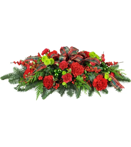 Christmas Traditions Centerpiece Christmas Traditions Centerpiece - Deck the halls—and your holiday table too! This festive red and green centerpiece will be that perfect final touch to your seasonal décor. It even smells like Christmas! A classic swag is arranged with red carnations, green baubles, pine, cedar, and more.