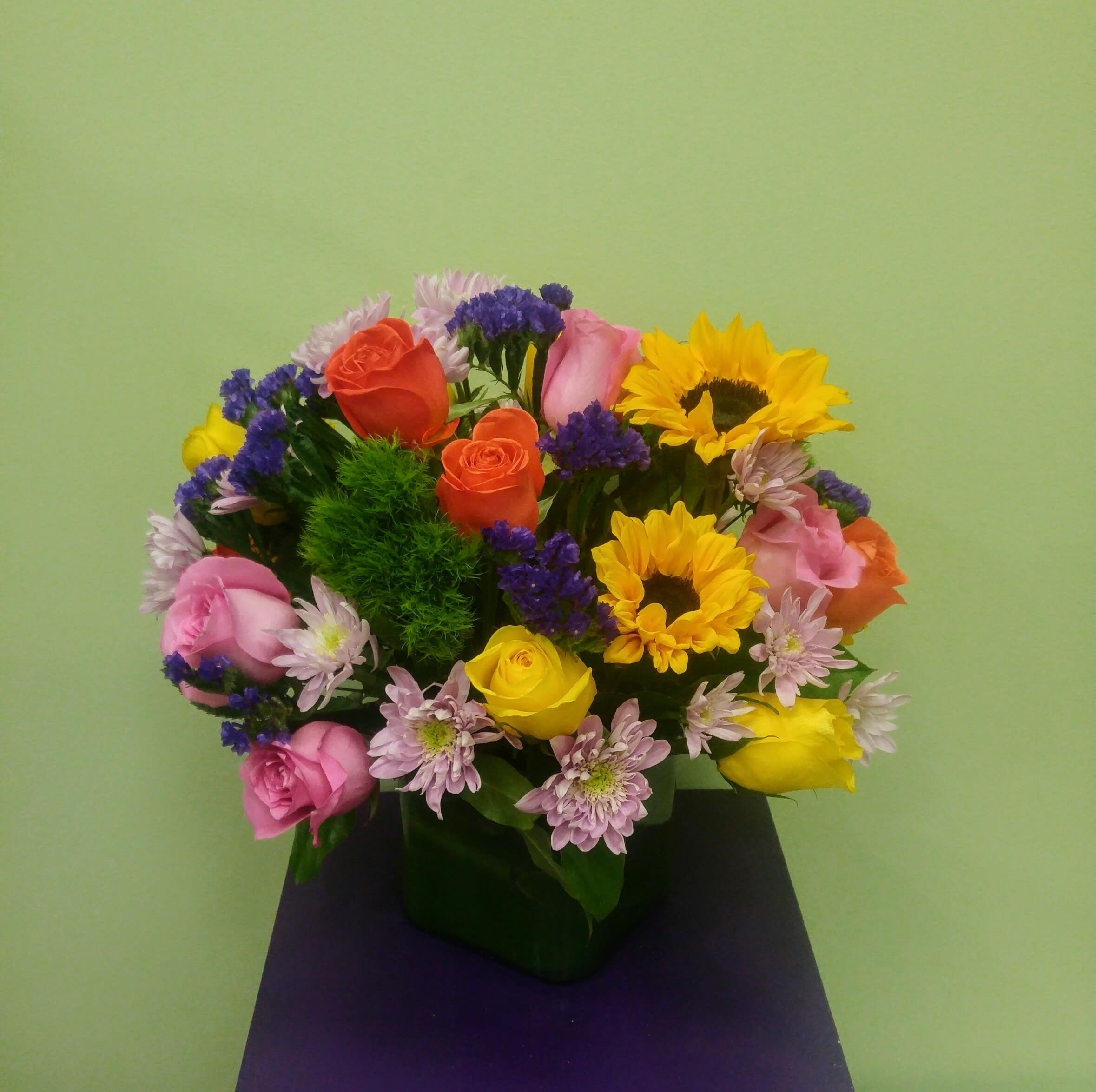 Into the Woods Bouquet - This bouquet includes assorted roses, sunflowers, chrysanthemum and exotic flowers. It is a colorful arrangement carefully designed in a cube vase. It is something that everyone will enjoy. 