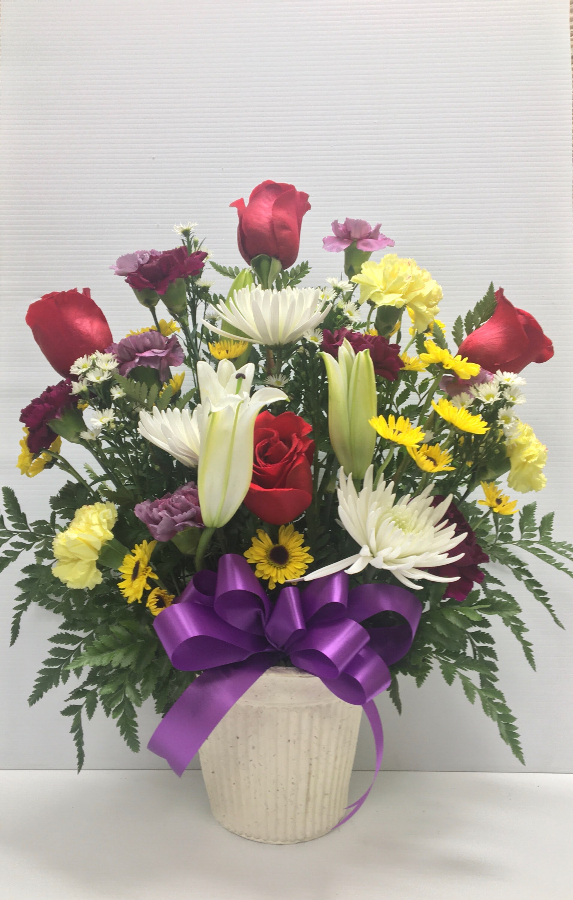 Our Condolences  - Arrangement includes Asiatic lillies, roses, carnations, mums and assorted greenery