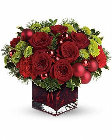 Teleflora's Merry &amp; Bright - You may not be able to guarantee a white Christmas, but with elegant touches like stunning red roses mixed with ornament balls and douglas fir, you can be assured of sending a merry and bright one! Gorgeous red roses and carnations along with brilliant green button chrysanthemums, shiny red ornament balls and winter greens are perfectly arranged in this very merry Christmas cube.