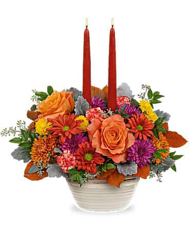 Teleflora's Rustic Chic Centerpiece - Sure to capture compliments, this fabulous fall centerpiece of colorful roses and mums looks lovely inside an artisanal stoneware serving bowl accented with reactive glaze. This arrangement includes orange roses, miniature orange carnations, lavender button spray chrysanthemums, bronze cushion spray chrysanthemums, dark bronze daisy spray chrysanthemums, brown copper beech, dusty miller, seeded eucalyptus, huckleberry and two dark burgundy candles. Delivered in a Rustic Harvest Bowl.