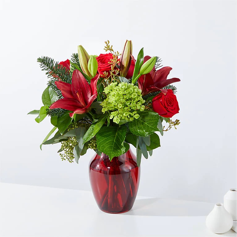 Merry Day Bouquet Merry Day Bouquet - Whether you're looking to decorate your home, surprise a loved one, or spread holiday cheer, the red and green blooms of our Merry Days Bouquet will be the perfect choice. Please Note: The bouquet pictured reflects our original design for this product. While we always try to follow the color palette, we may replace stems to deliver the freshest bouquet possible, and we may sometimes need to use a different vase. Our Florist designs Rose, Lily, Hydrangea, Eucalyptus, Christmas Greens in Red Vase.