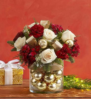 Glorious Christmas -   Leave them rocking around the Christmas décor with this truly original arrangement. Crafted from roses and carnations mixed with festive hypericum and evergreens, it's gathered fresh in a glass vase filled with shimmering ornament balls. Makes a stunning centerpiece, a thank you gift for hostesses or a gorgeous addition to any gathering of family and friends.   Item # 99076 